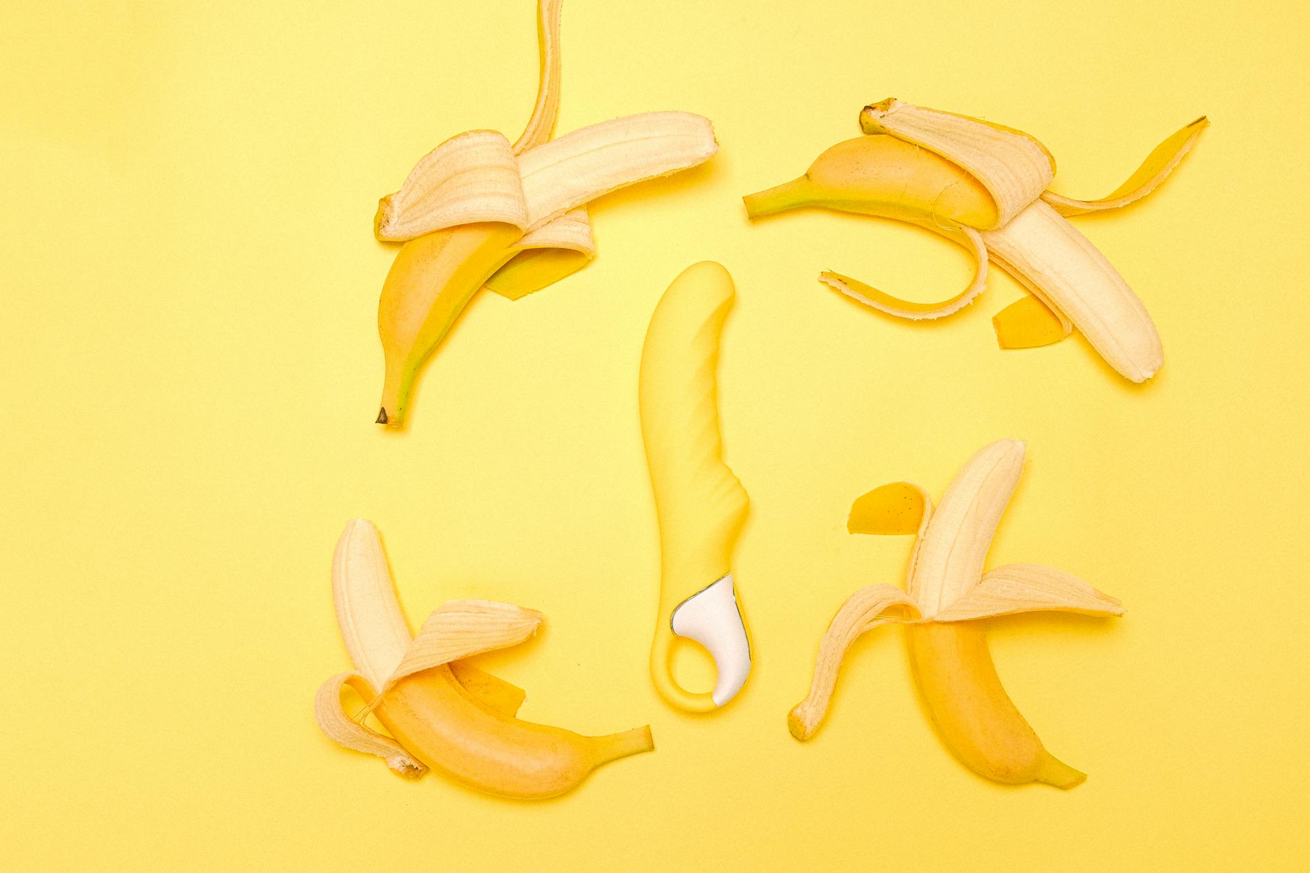 Vibrator citron jaune entouré de bananes pelées sur fond jaune vif