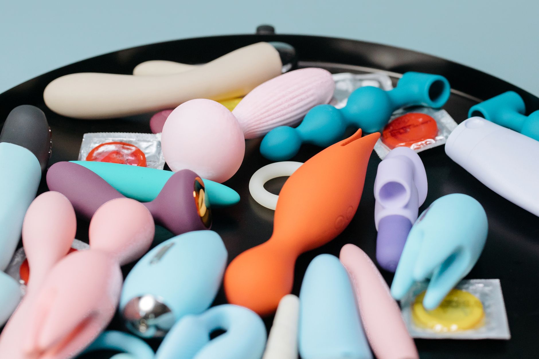 Une collection variée de jouets sexuels sur un plateau noir, mettant en avant différentes formes et couleurs.