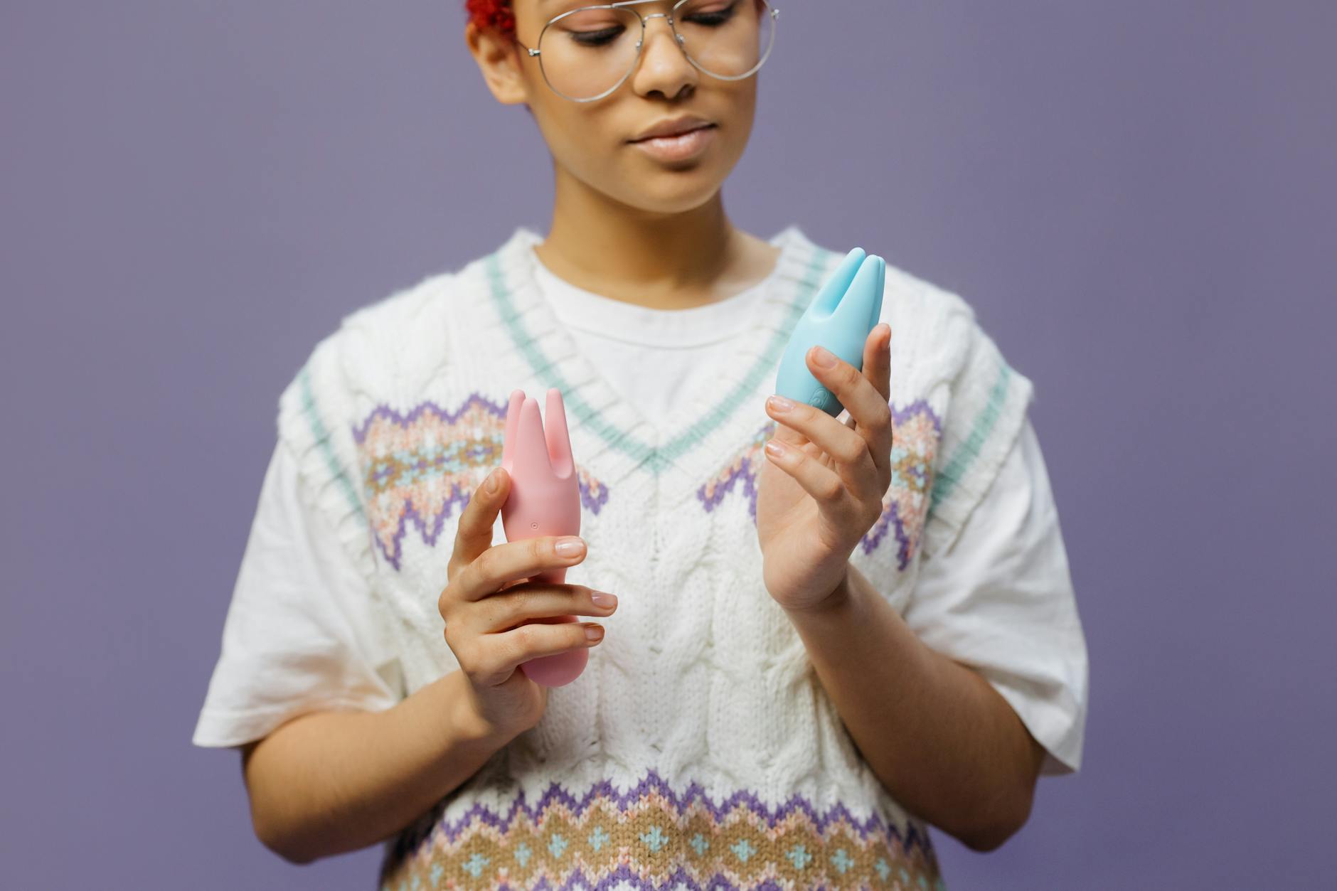 Femme portant des lunettes tenant des vibrateurs en silicone bleu et rose d'une manière contemplative